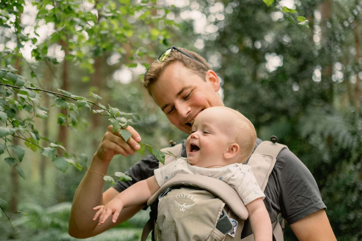 Osprey Poco Soft Child Carrier LT - Tan Concrete in use by a parent outdoors, enjoying nature with a smiling baby | Babymaxi