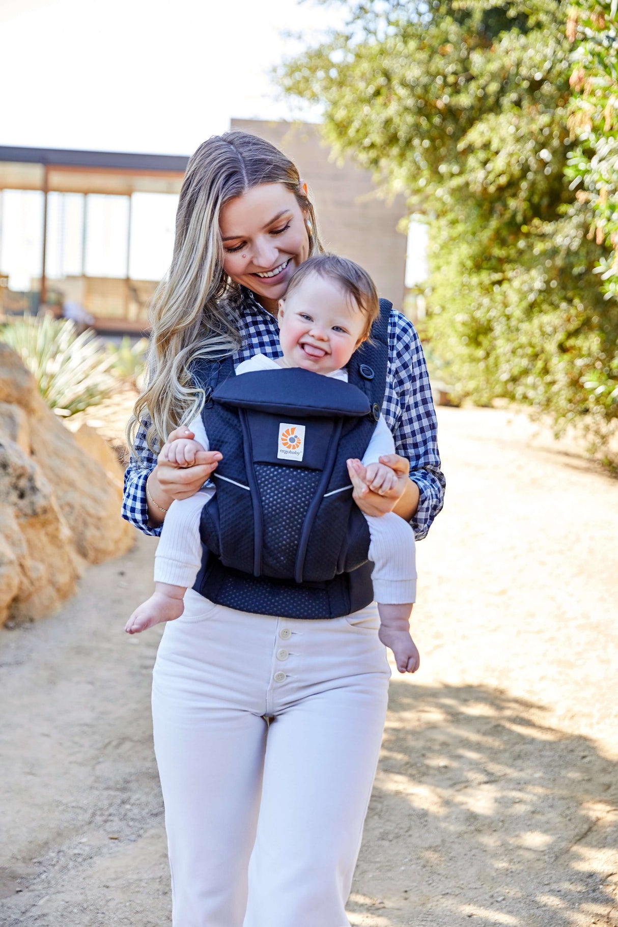 Mom carrying baby in Ergobaby Omni Breeze - Midnight Blue carrier outdoors, showcasing breathability and comfort | Babymaxi