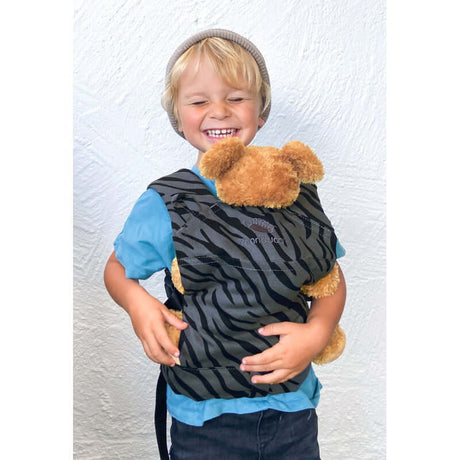 Happy child wearing Manduca Doll Carrier - Zebra with cuddly toy, showcasing organic cotton design | Babymaxi