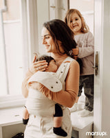 Mom using Marsupi Classic - Natur baby carrier with happy baby, child playing nearby | Babymaxi