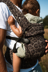 Male parent wearing Nomad Air carrier during outdoor daytime activity with toddler