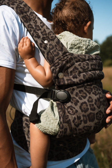 Male parent wearing Nomad Air carrier during outdoor daytime activity with toddler