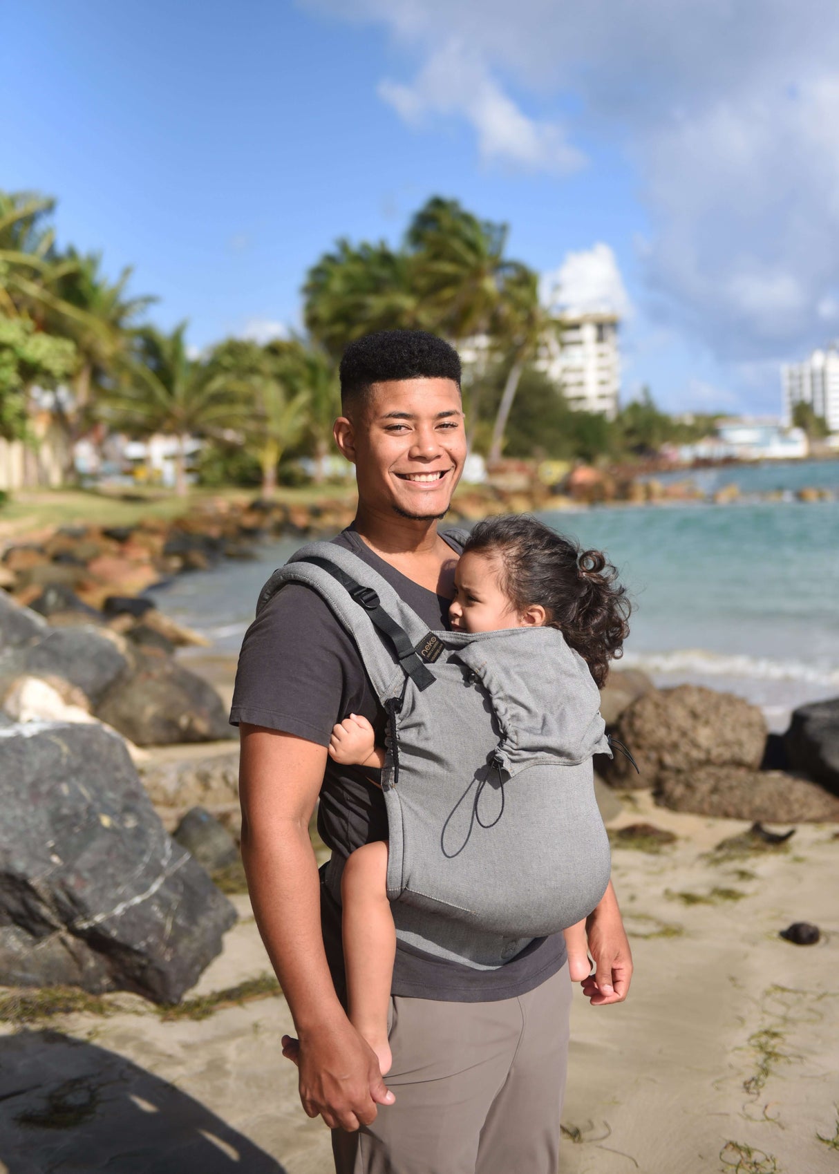 Father carrying child in Neko Switch Toddler Carrier - Bold on beach, showcasing ergonomic design and comfort | Babymaxi