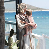 Mom carrying toddler in Neko Switch Toddler - Mocha carrier by the beach, showcasing comfort and ergonomic design | Babymaxi