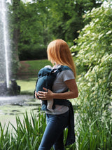 Woman using Storchenwiege Bondima Wrap Baby Carrier - Turquoise in a serene outdoor setting | Babymaxi