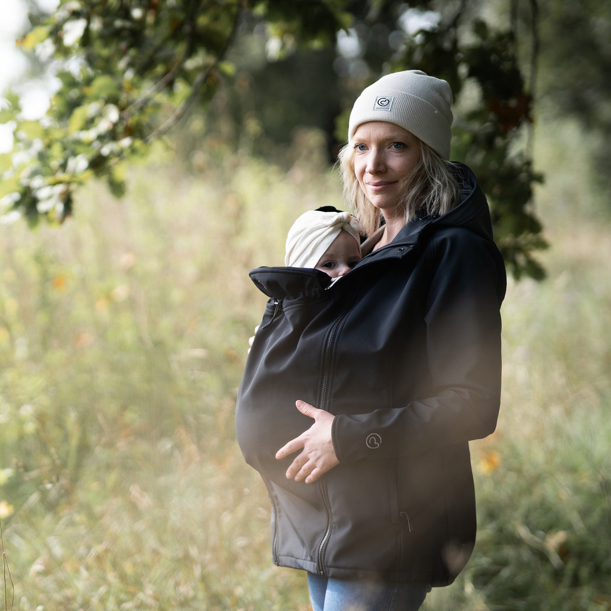 Mamalila Softshell Babywearing Jacket Allrounder Fit Black, mother carrying baby on front outdoors